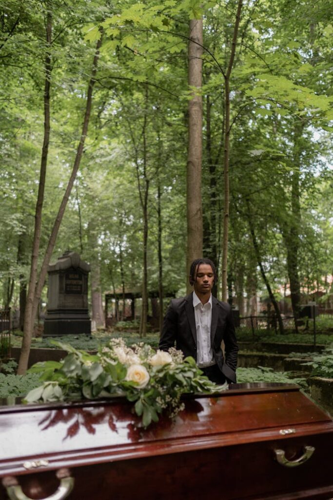 A Man in Black Suit Standing In Front of the Coffin